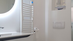 A modern bathroom with a white sink, a toilet, and a towel rack.