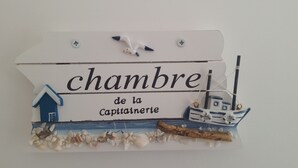 A decorative sign with the text "chambre de la Captainerie" and maritime elements like a ship and a house.