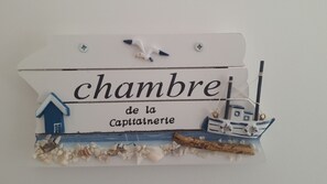 Ein dekoratives Schild mit dem Text "chambre de la Captainerie" und maritimen Elementen wie einem Schiff und einem Haus.
