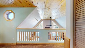 Une pièce spacieuse avec un plafond en pente, une lucarne et un balcon doté de balustrades en bois.
