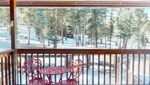 Un balcon avec vue sur une forêt enneigée et un espace piscine.