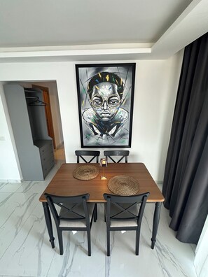 Ein Essbereich mit einem Holztisch, vier Stühlen und einem gerahmten Kunstwerk an der Wand.