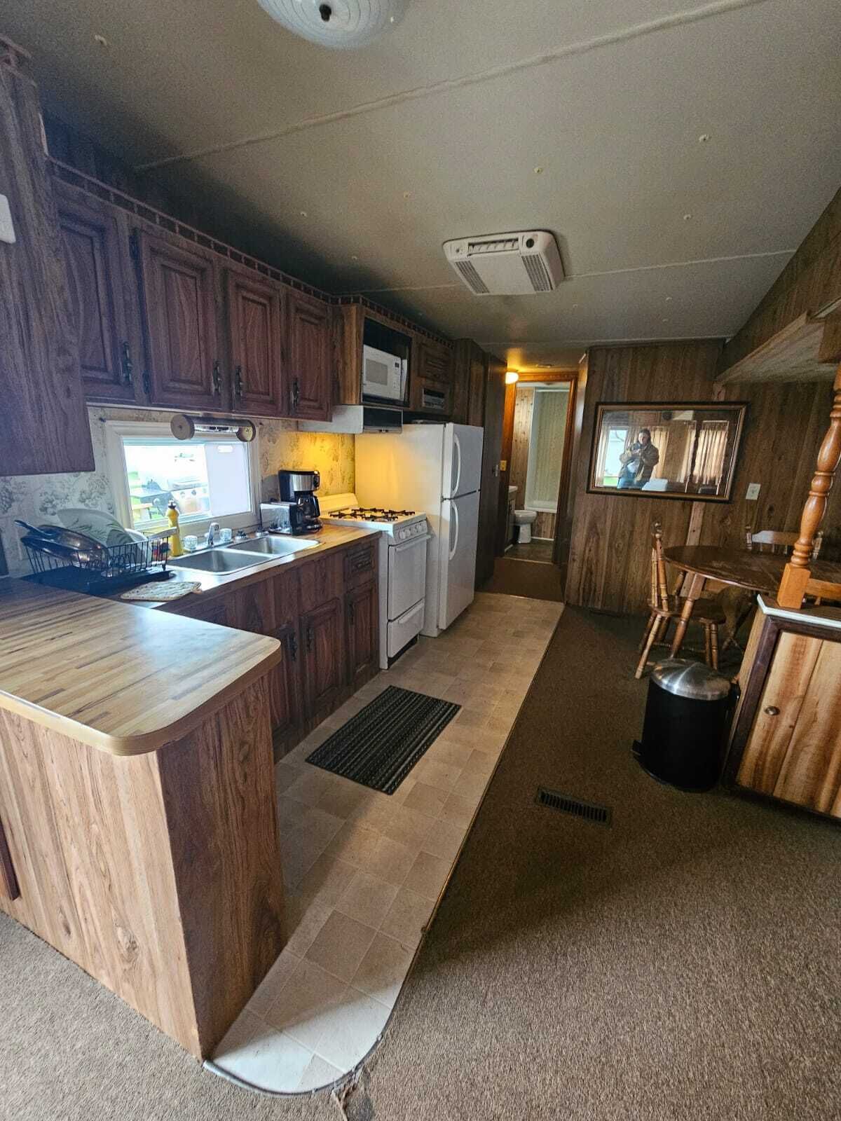 Una cocina con armarios de madera, microondas, estufa y refrigerador.