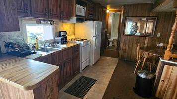 Una cocina con armarios de madera, microondas, estufa y refrigerador.