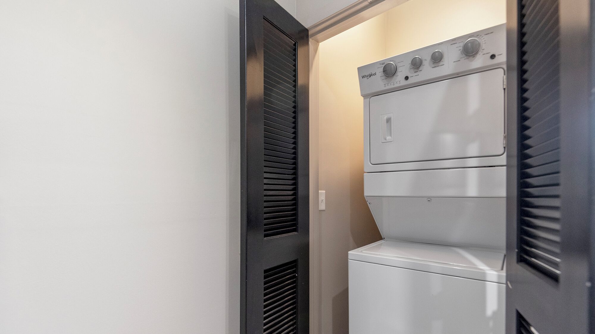Une buanderie moderne et compacte, dotée d’un lave-linge et d’un sèche-linge intégrés, se distinguant par son design épuré et ses commandes minimalistes.