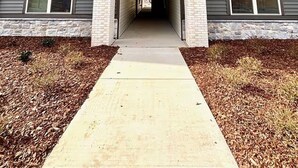 A multi-story building with a central entrance, a covered walkway, and a sign indicating a parking area. - Landing Apartments - West Asheville (Asheville)