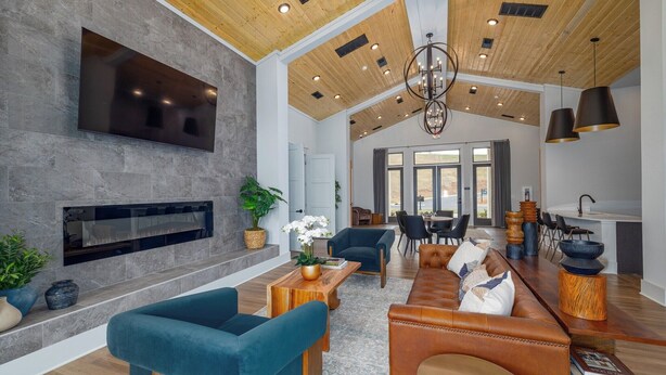 A spacious living area with a fireplace, modern furniture, and a high ceiling with exposed beams. - Landing Apartments - West Asheville (Asheville)