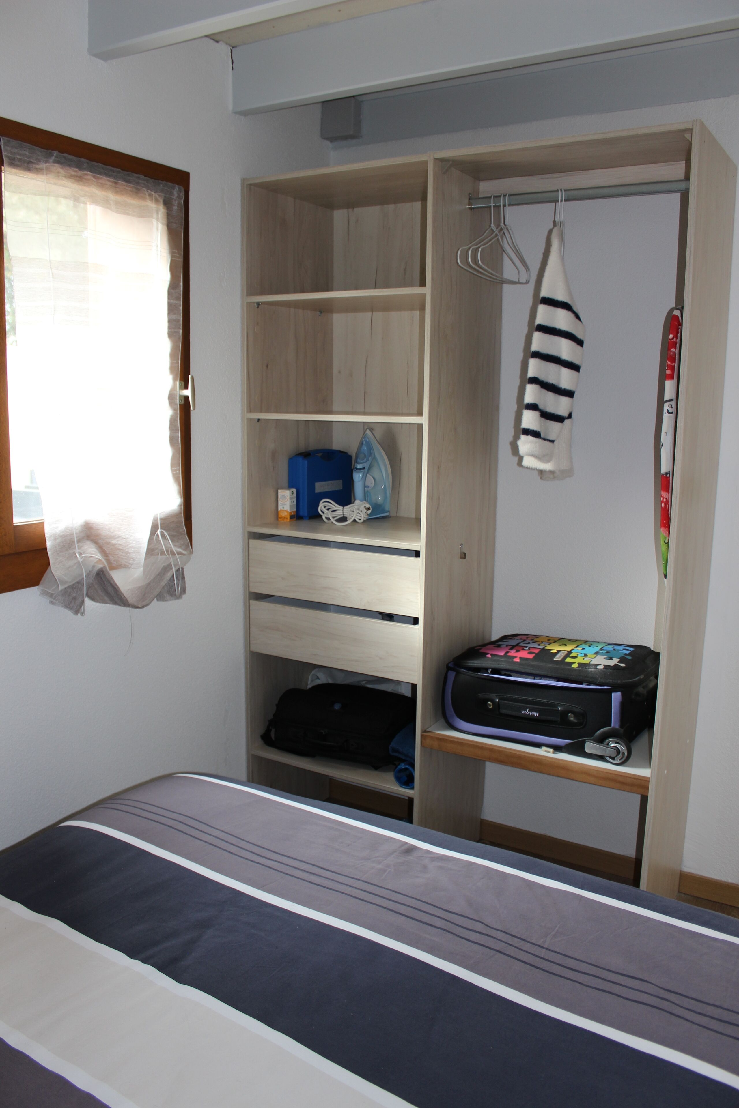 A bedroom with a bed, a wardrobe, and a suitcase.