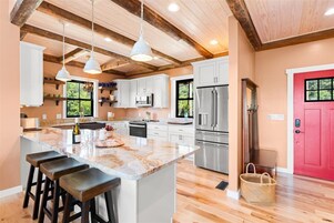A modern kitchen with a large island, stainless steel appliances, and wooden flooring.