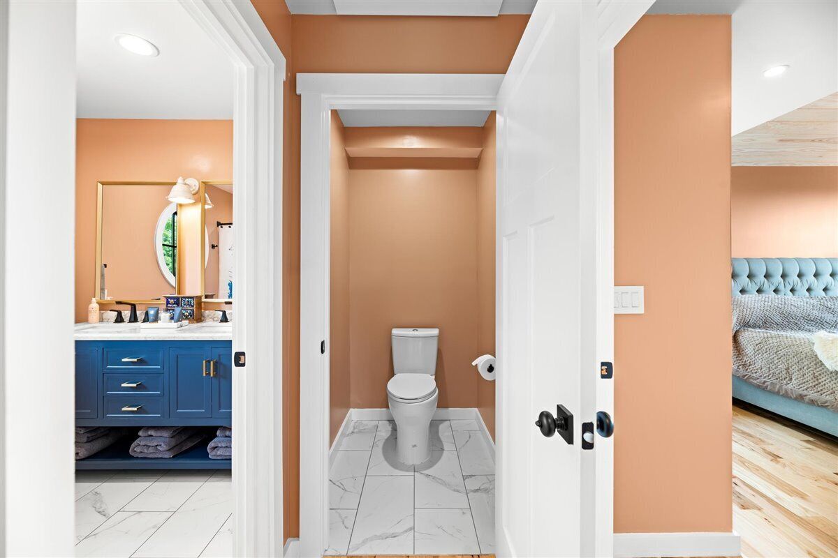 Une salle de bain avec des toilettes, un lavabo avec un miroir et un meuble bleu contenant des serviettes.