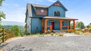 Una casa a due piani con facciata blu, una porta rossa e un portico con ringhiere in legno.