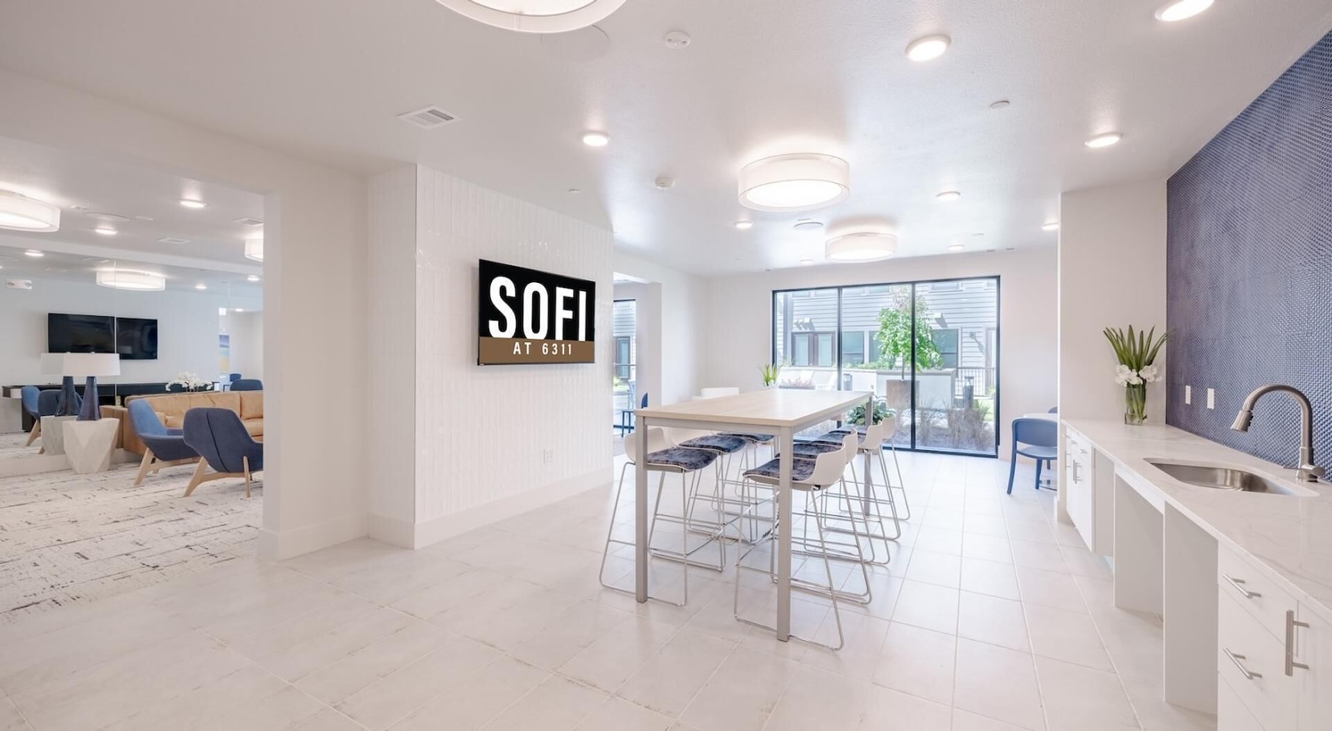 A modern kitchen with a bar area, a dining space, and a living area with seating.