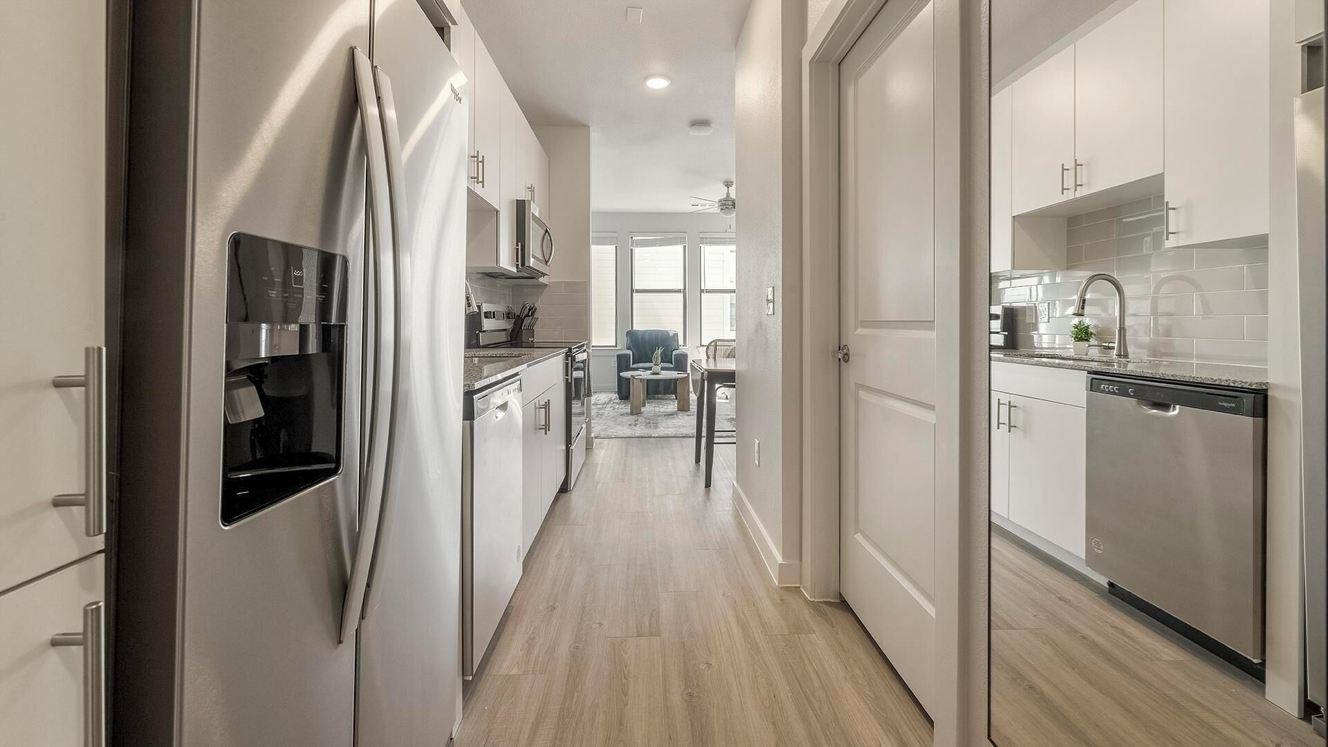 Una cucina moderna con elettrodomestici in acciaio inossidabile, un'area pranzo con tavolo e sedie, e vista su un soggiorno con divano e tavolino.