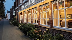 Hotel Osterkrug Husum with a brick facade, large windows, and a sign indicating it is a restaurant and hotel. - Hekmat Apartments Fernsicht Schobüll (Husum)