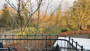 A wooden deck with metal railings, a hexagonal table, and two chairs. - Hekmat Apartments Fernsicht Schobüll (Husum)
