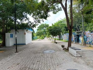 Ein gepflasterter Weg, gesäumt von Bäumen, mit einem Wandgemälde auf der rechten Seite.