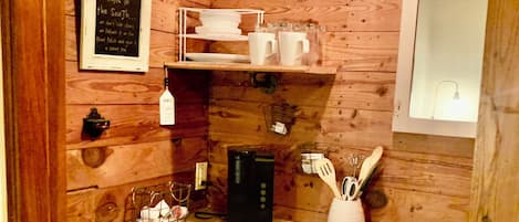A compact kitchen with wooden walls, a coffee maker, a microwave, and a small sink.
