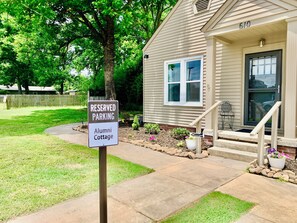 A house with a 'RESERVED PARKING' sign for 'Alumni Cottage.'