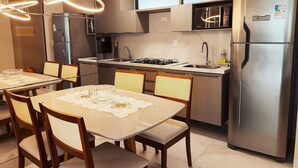 A modern kitchen with a dining area, stainless steel appliances, and a clean, contemporary design. - Luxor Tambaú (João Pessoa)