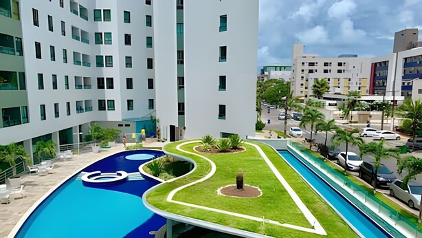 A modern hotel with a swimming pool, a landscaped garden, and a view of surrounding buildings. - Luxor Tambaú (João Pessoa)