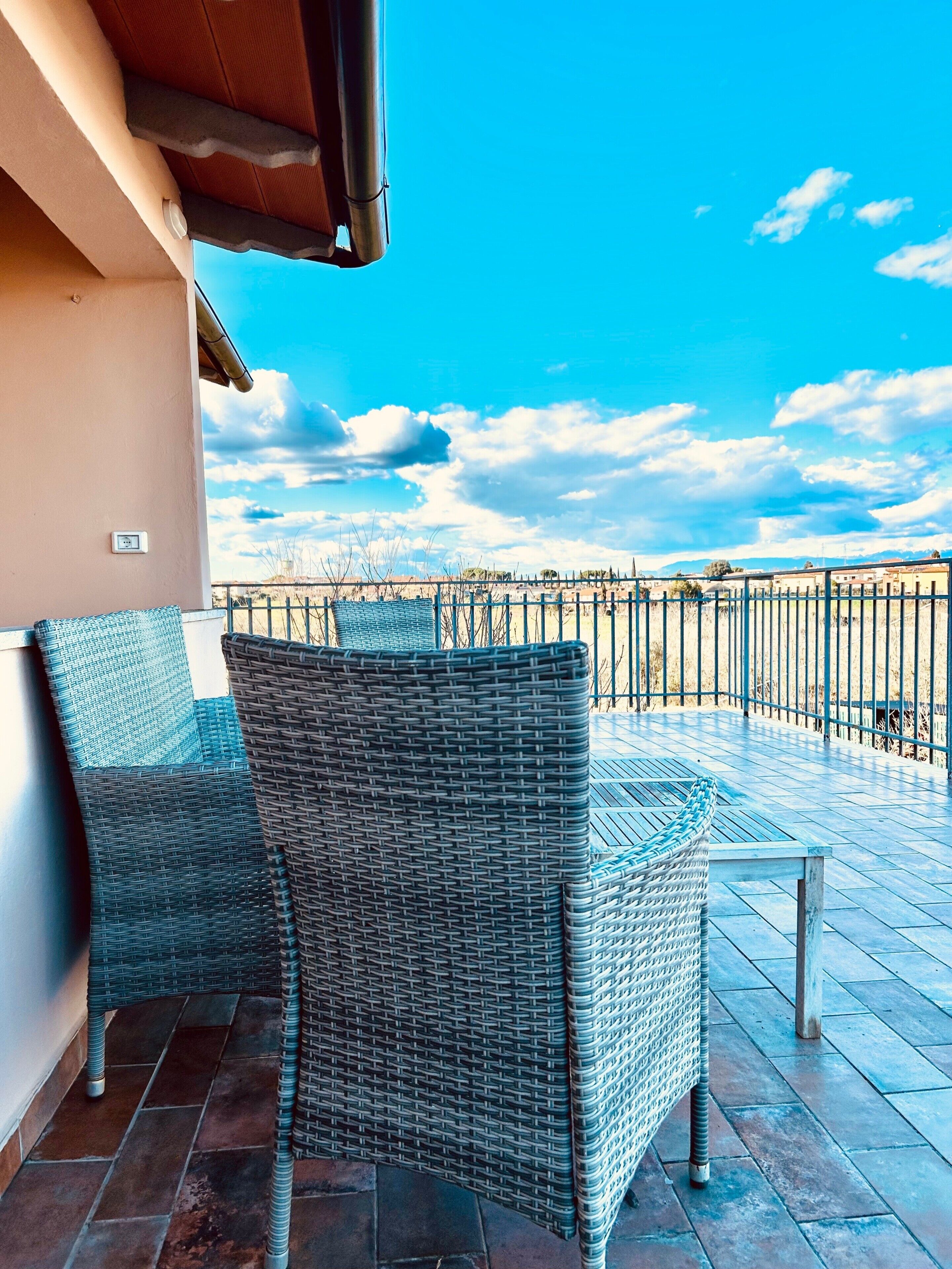 A balcony with wicker furniture and a view of the landscape.
