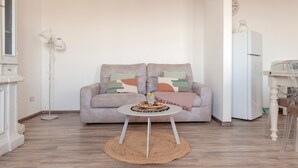 Un salon comprenant un canapé, une table basse ronde, un lampadaire et un réfrigérateur.