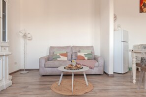 Un salon comprenant un canapé, une table basse ronde, un lampadaire et un réfrigérateur.