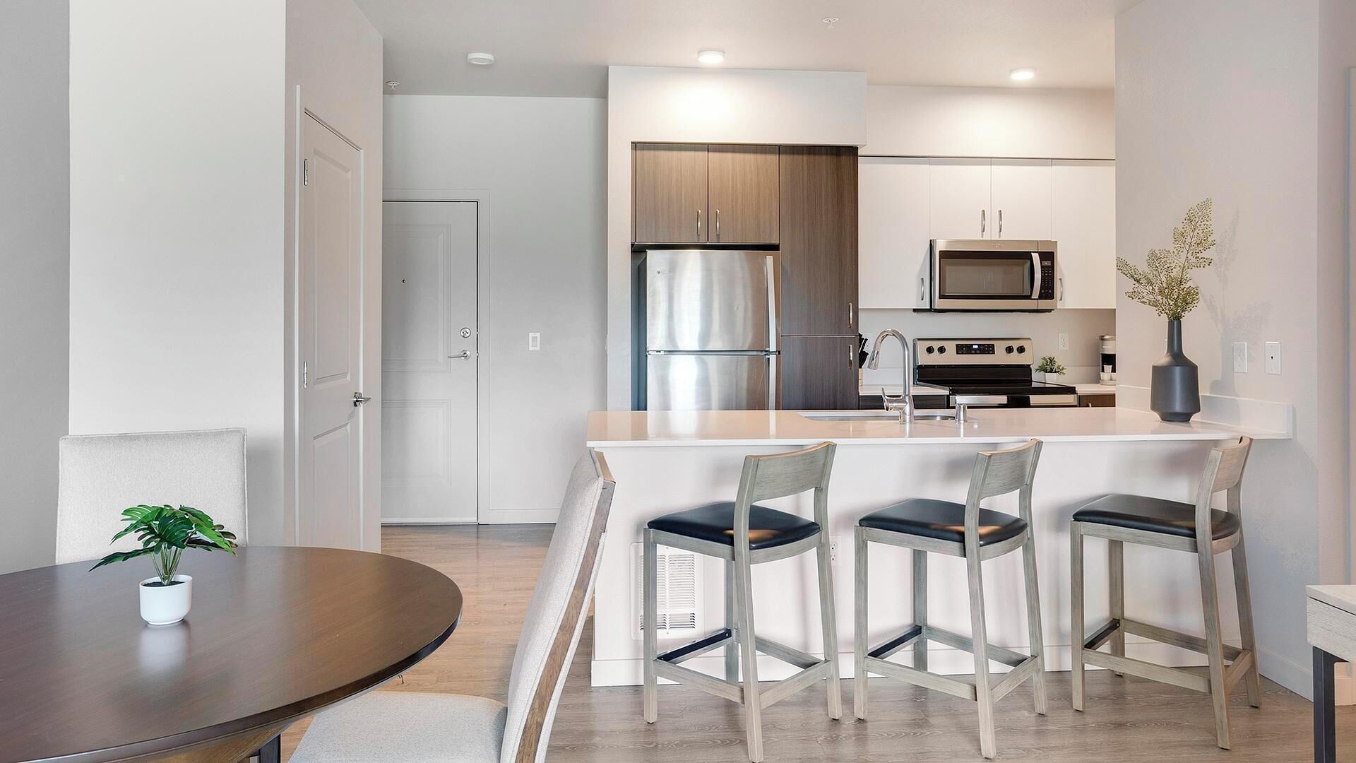 A modern kitchen with a central island, stainless steel appliances, and a dining area with a round table and four chairs.