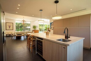 A modern kitchen with a large island, bar stools, and a built-in oven.
