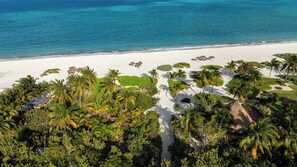 An aerial view of a beach resort with palm trees, a white sandy beach, and clear blue water. - Villa Marazul | 5BR | Beach & Golf Access (Cancún)