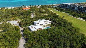 Luchtbeeld van een resort met een zwembad, weelderige begroeiing en een strand.