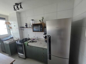 Une cuisine moderne équipée d’un réfrigérateur en acier inoxydable, d’un four à micro-ondes, d’une cuisinière à gaz et d’un évier.