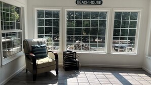 A room with a large window, a chair, and a sign that reads "BEACH HOUSE". - Charming Mill Beach Cottage by the Sea (Brookings)