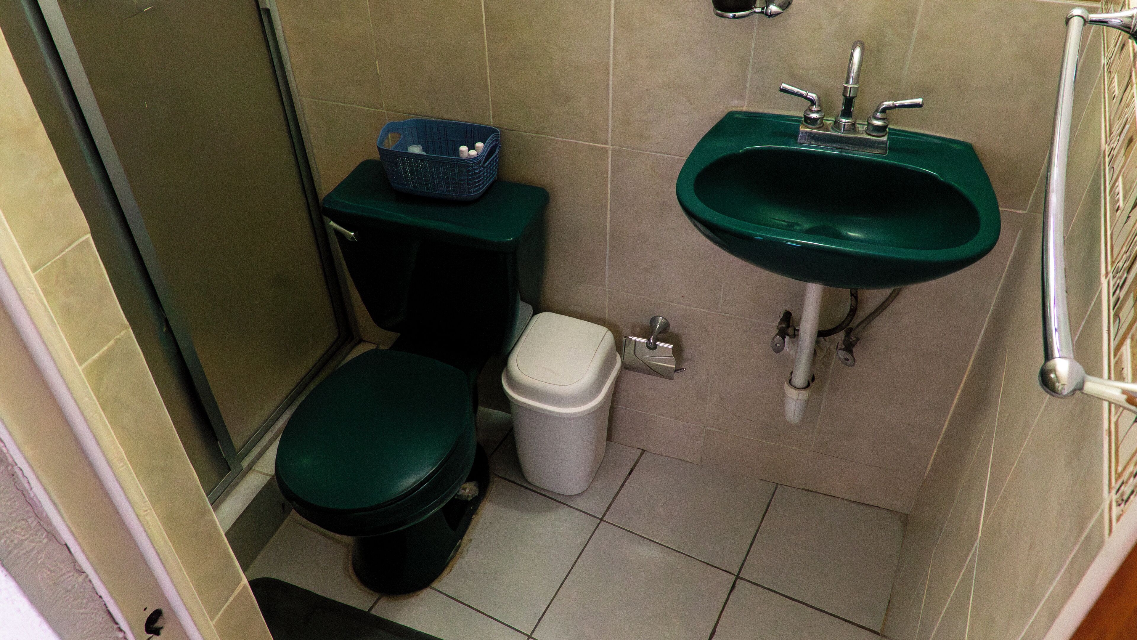 Een kleine badkamer met toilet, prullenbak en wastafel.