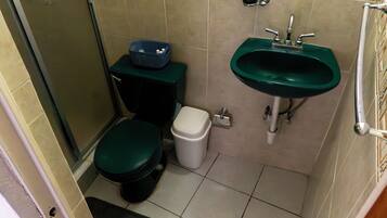 Een kleine badkamer met toilet, prullenbak en wastafel.