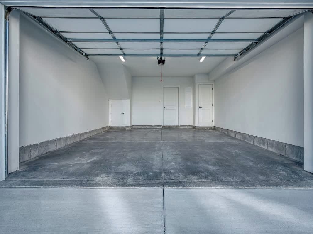 A spacious garage with a concrete floor, metal roof, and white walls.