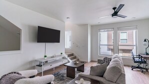 A modern living room with a flat-screen TV, a sofa, a coffee table, and a desk with a lamp. - Landing Furnished Apartments - Billings, MT (Billings)