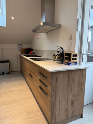 A modern kitchen with a wooden island, built-in appliances, and a window for natural light.