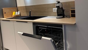 Eine moderne Küche mit Geschirrspüler, Kaffeemaschine und Schneidebrett.