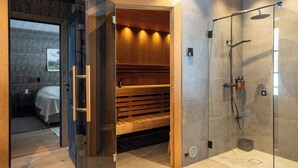 Un baño moderno con cabina de ducha de vidrio, un banco de madera y un inodoro a la vista.