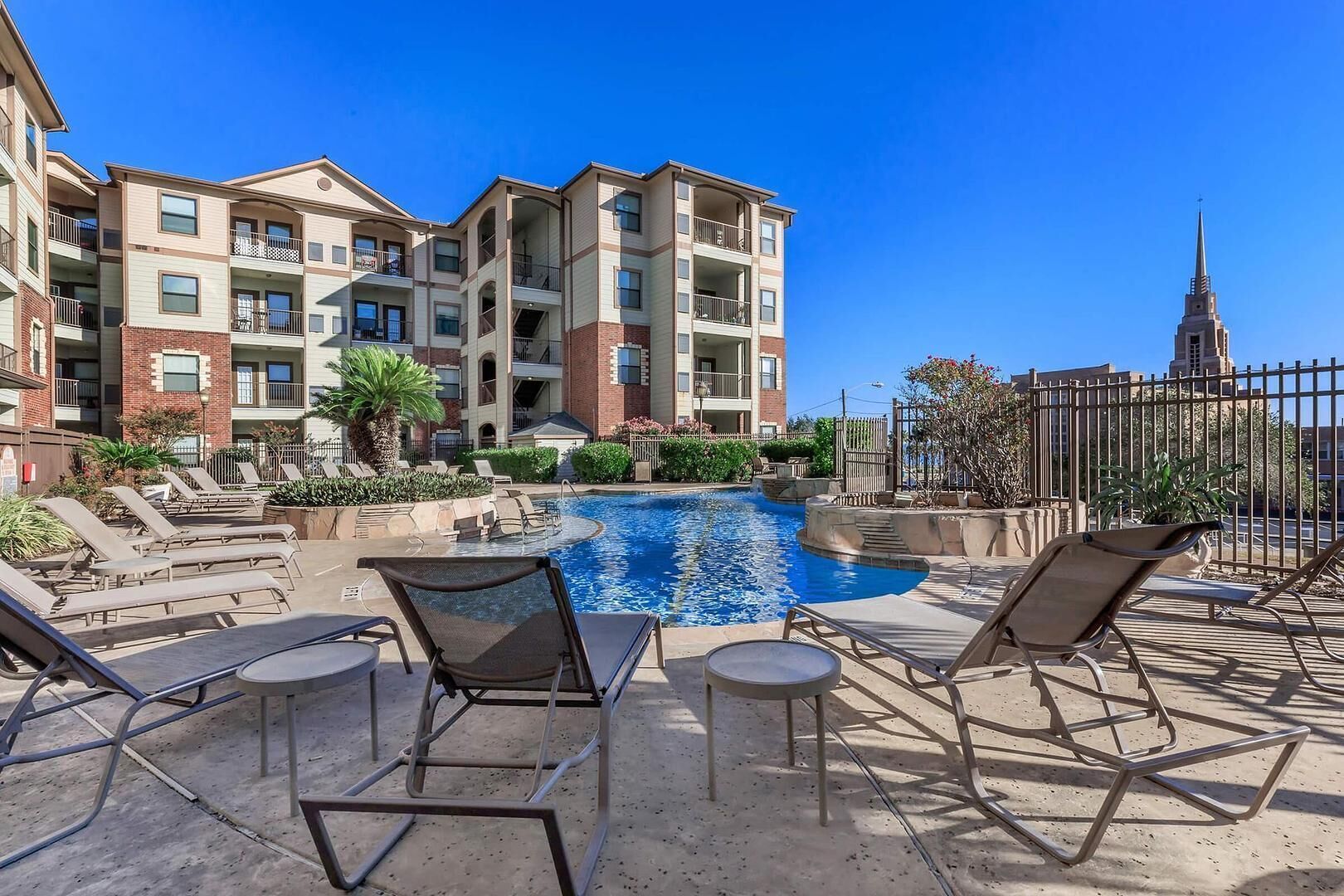 A pool area with lounge chairs and a view of apartment buildings.