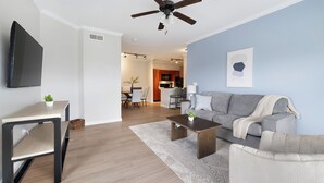 Una sala de estar moderna con un sofá gris, una mesa de centro, un televisor y un ventilador de techo.