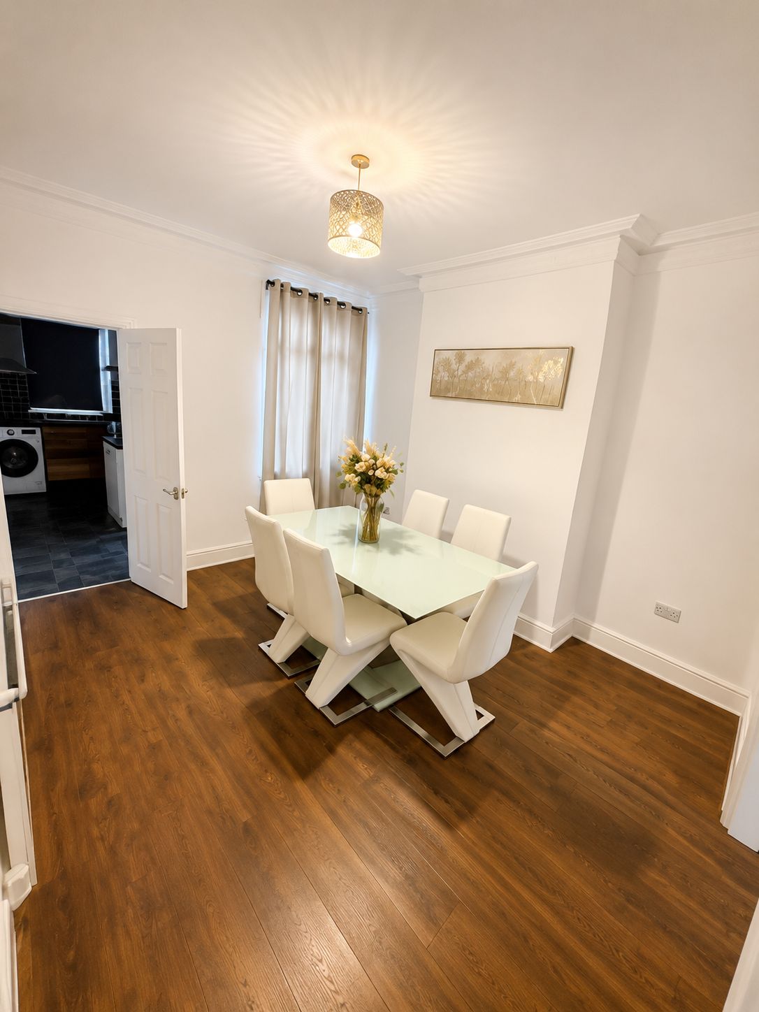 A dining area with a table, chairs, a vase with flowers, and a painting on the wall. - Stay for 12 | Families/Contractors | Near Doncaster Station+City Centre |Parking (Doncaster)
