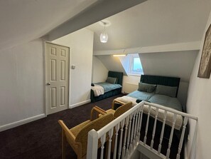 A bedroom with two beds, a window, a door, and a crib.