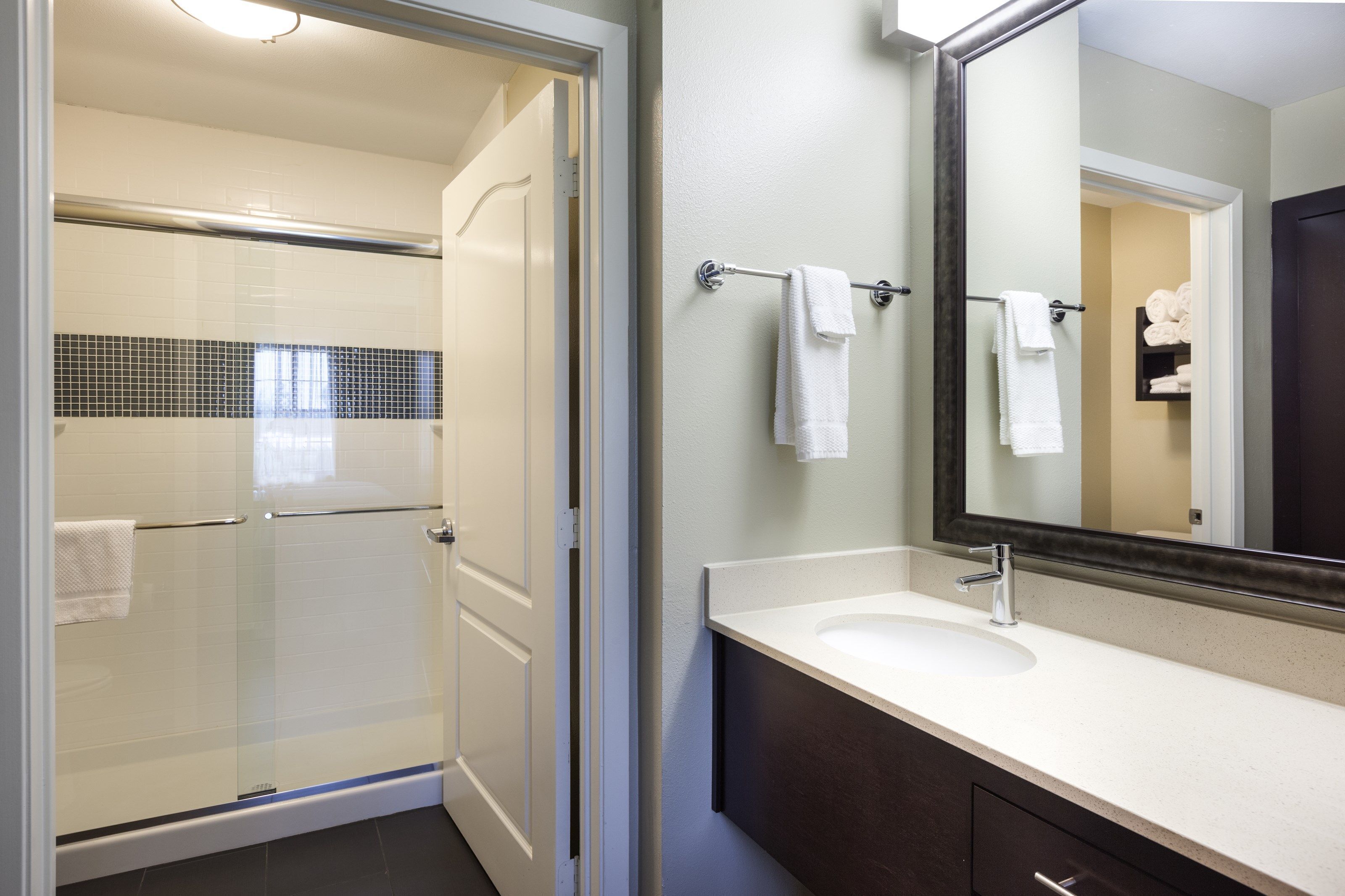 A modern bathroom with a glass-enclosed shower, a white sink, and a large mirror.