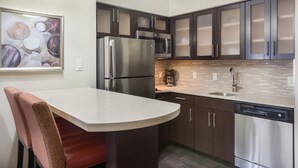 A modern kitchen with stainless steel appliances, dark cabinetry, and a white countertop. - Studio Suite in Houston's Energy Corridor | Free Breakfast + 24h Business Center (Houston)