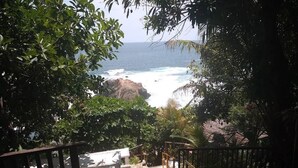 Una scala che conduce a una spiaggia con vista sull'oceano, circondata da alberi e una ringhiera in legno.