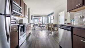 Cocina moderna con electrodomésticos de acero inoxidable, armarios de madera y un comedor con vistas al exterior.