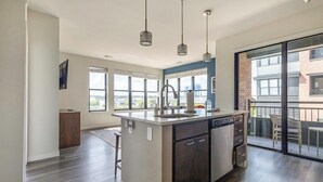 Una cocina moderna con una isla central, ventanas amplias y un balcón con mobiliario de exterior.