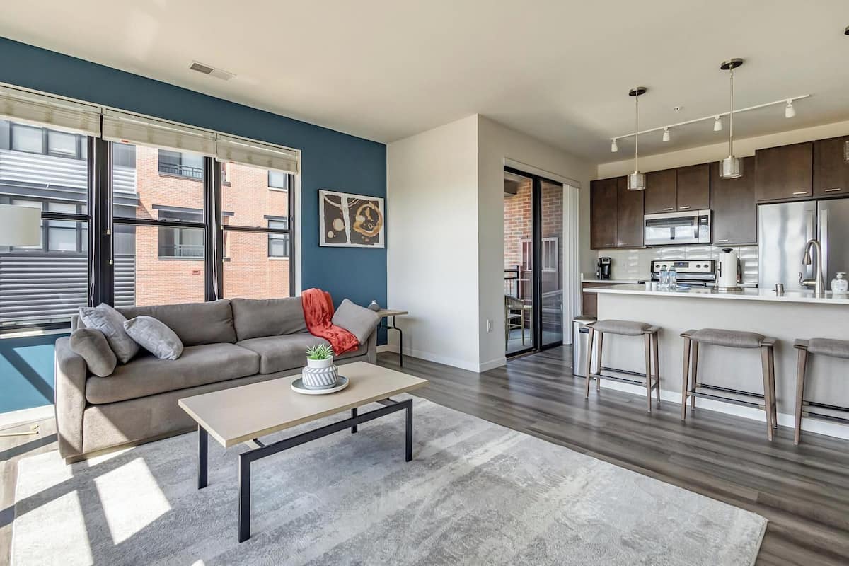 Un appartamento moderno con soggiorno, cucina e un balcone con vista su un edificio in mattoni.